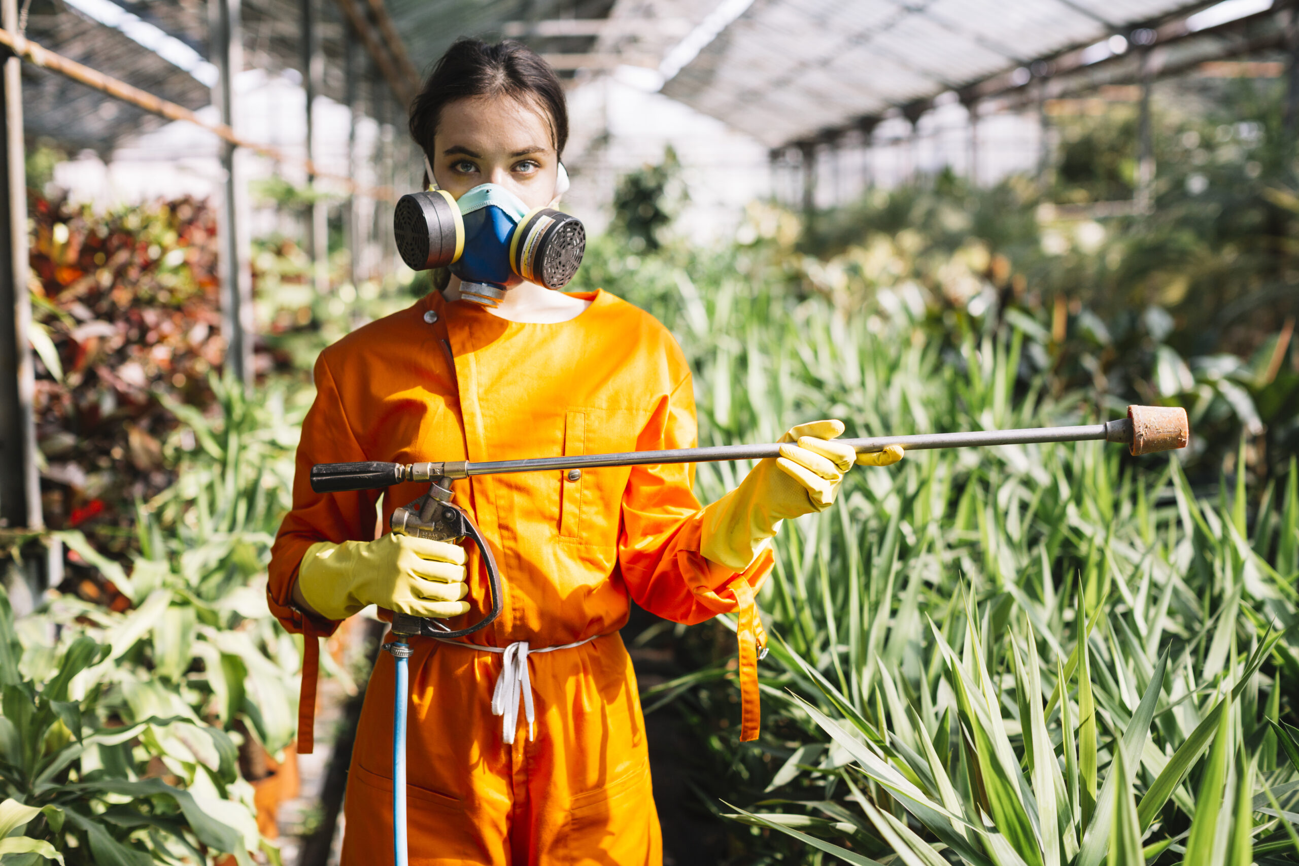 portrait-female-gardener-holding-sprayer-greenhouse